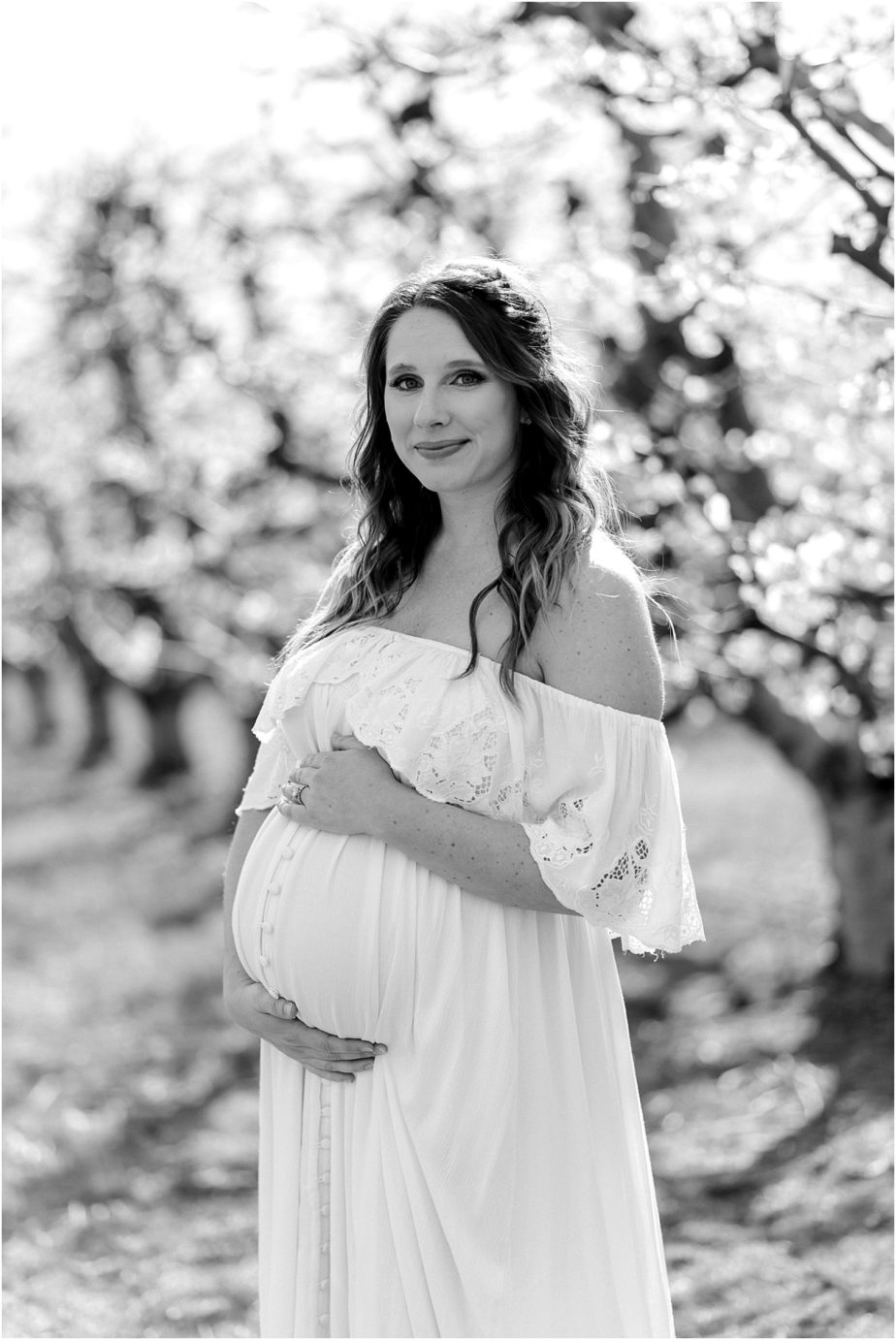 County Maternity Session couple posing in cherry blossoms orchard