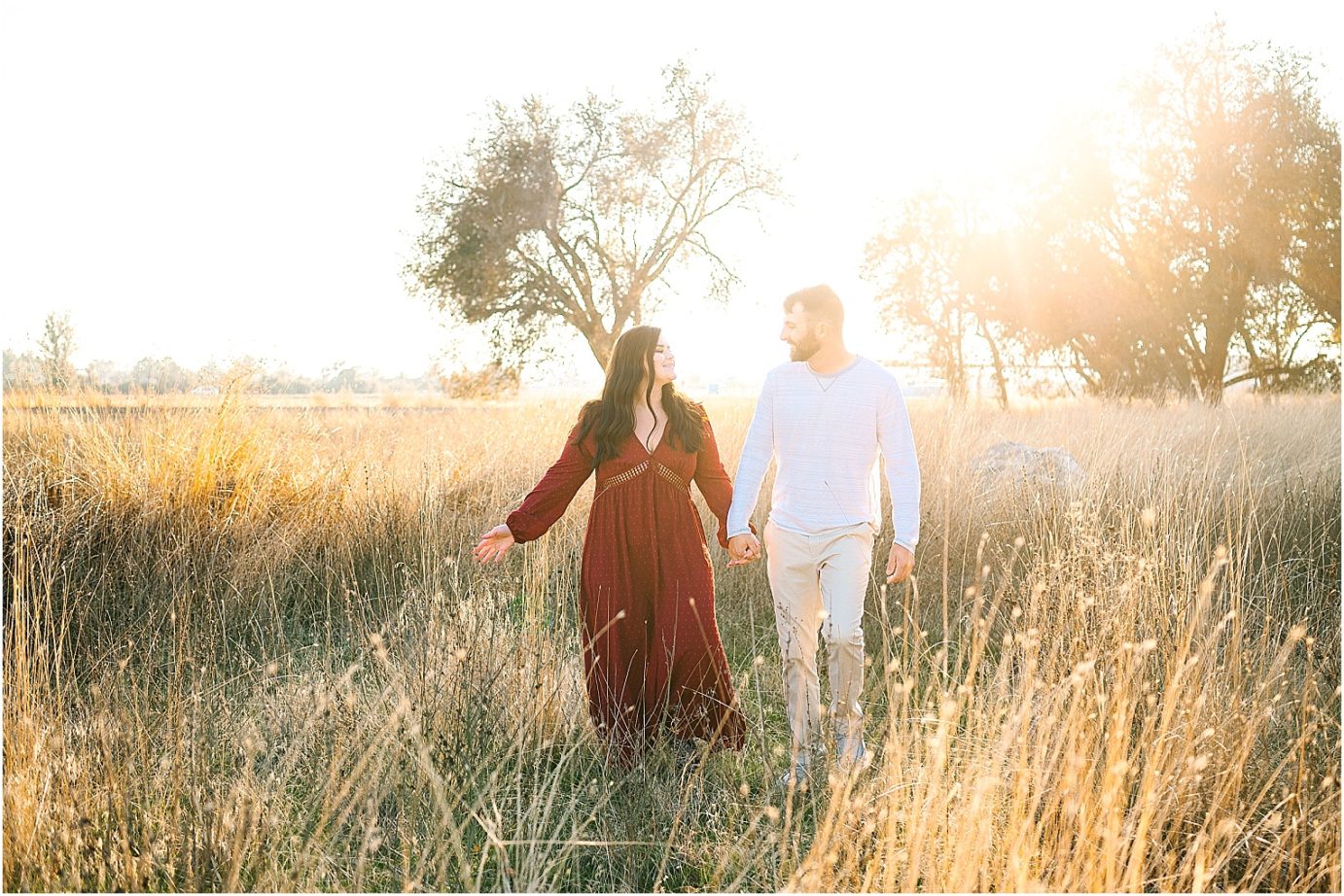 couple walking hand in hand through a field 
