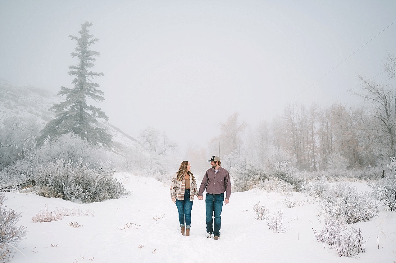 Snowy ellensburg engagement session couple walking through the snow