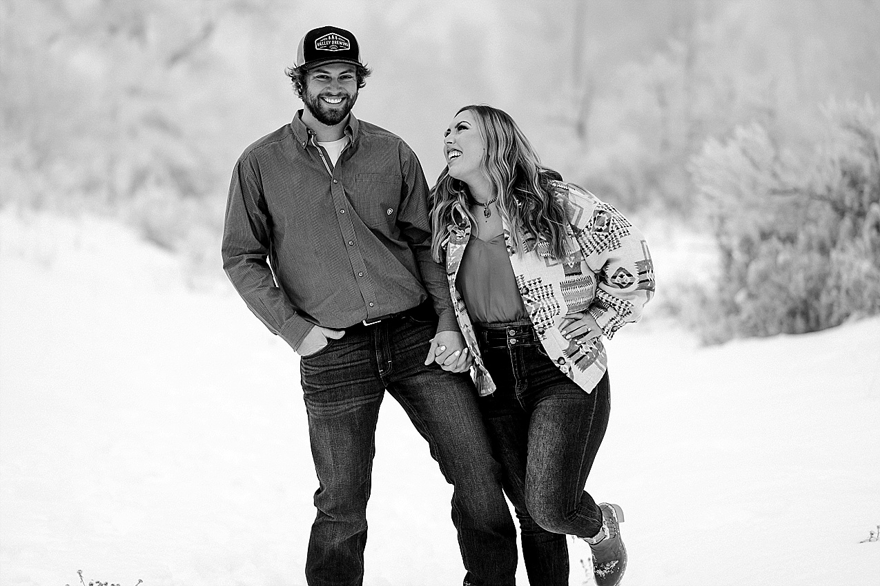 Snowy ellensburg engagement session couple laughing while walking in the snow